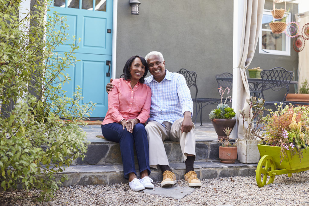 Senior couple sit on steps outside their house